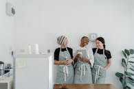 在工作日，室内空间狭小的现代咖啡馆里，几位不同种族的女性咖啡师系着围裙，站在墙边，微笑着看向彼此