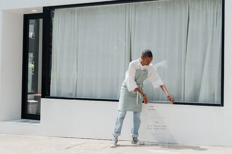 Diligent Black Female Worker Setting Signboard Outside Cafeteria At Sunny Day