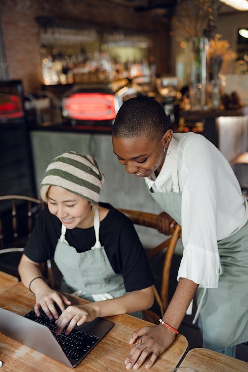 Smiling diverse baristas using laptop in modern cafe