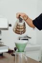 Unrecognizable female barista preparing delicious coffee in glass coffeemaker and pouring hot water during at table in modern cafeteria
