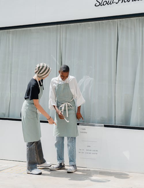 Woman pointing at transparent billboard of cafe to black colleague on street