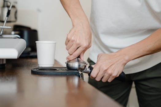Barista tamping espresso for fresh coffee preparation in a modern café setting.