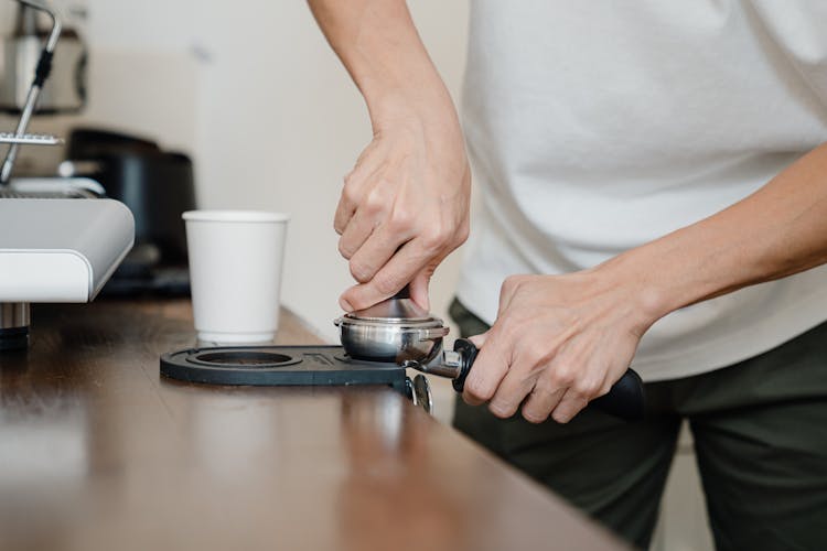 Crop Barista Preparing Coffee Pod In Holder With Tamper