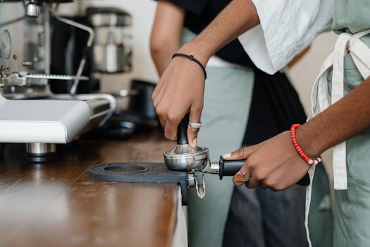 Close-up of a barista using a portafilter and tamper to make espresso in a café.