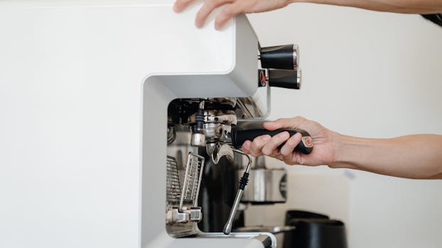 Close-up of hands operating an espresso machine, making coffee indoors.