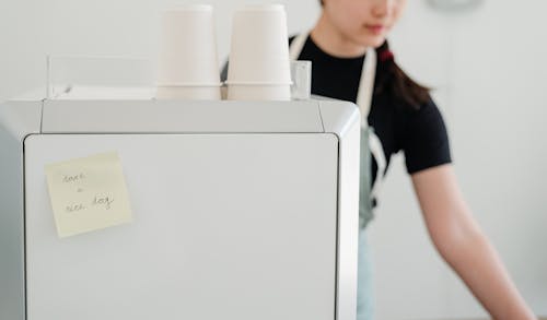 Crop woman in apron near coffee machine