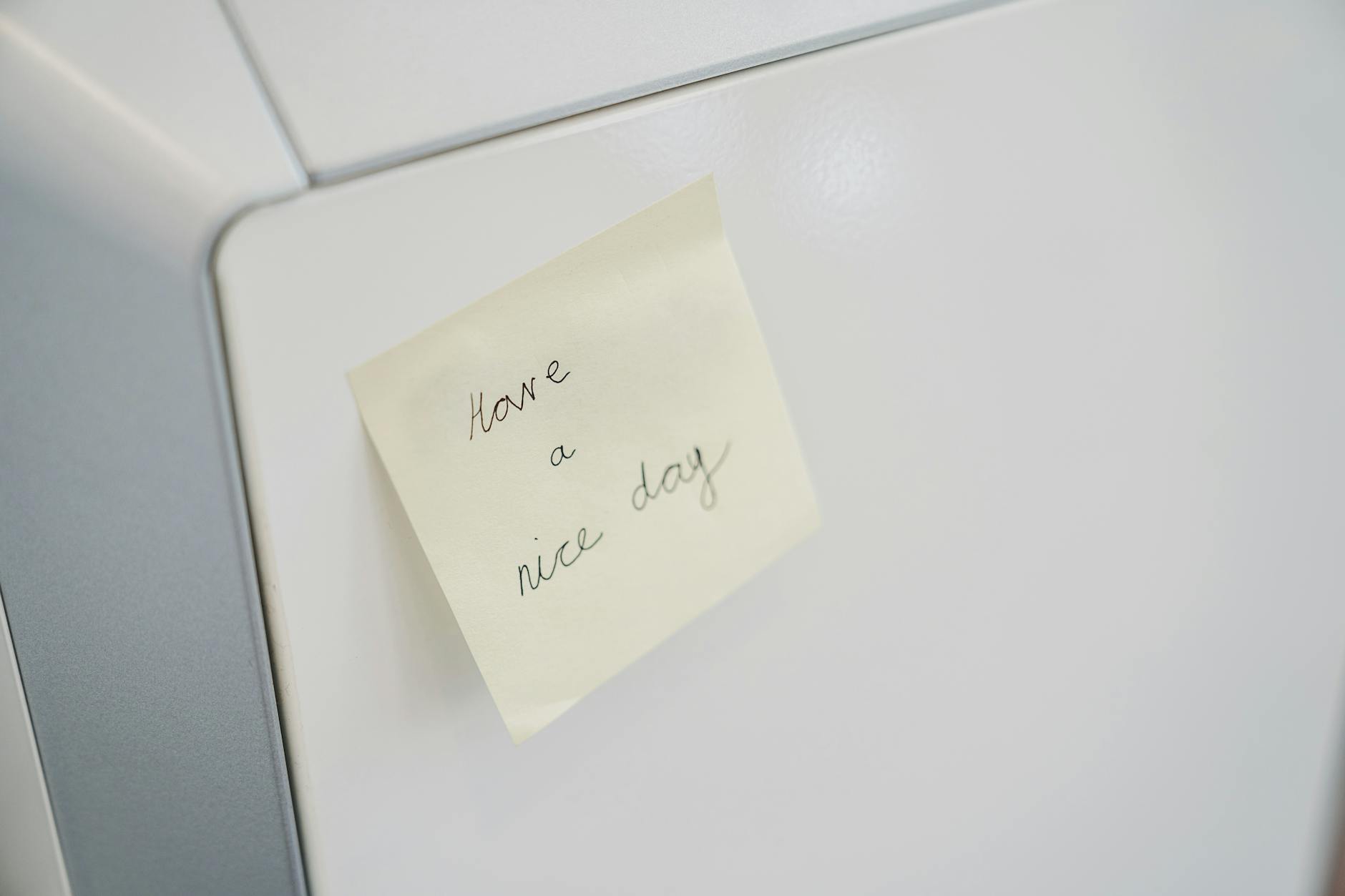 A close-up of a sticky note with 'Have a nice day' on a white surface, conveying positivity.