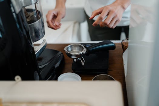 Barista hands preparing espresso with a portafilter in a modern café setting.