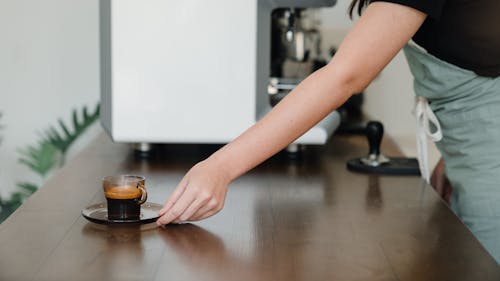 Crop barista serving aromatic espresso in coffee counter