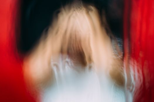 Through glass view of faceless person representing scary zombie near bright red blood fluids