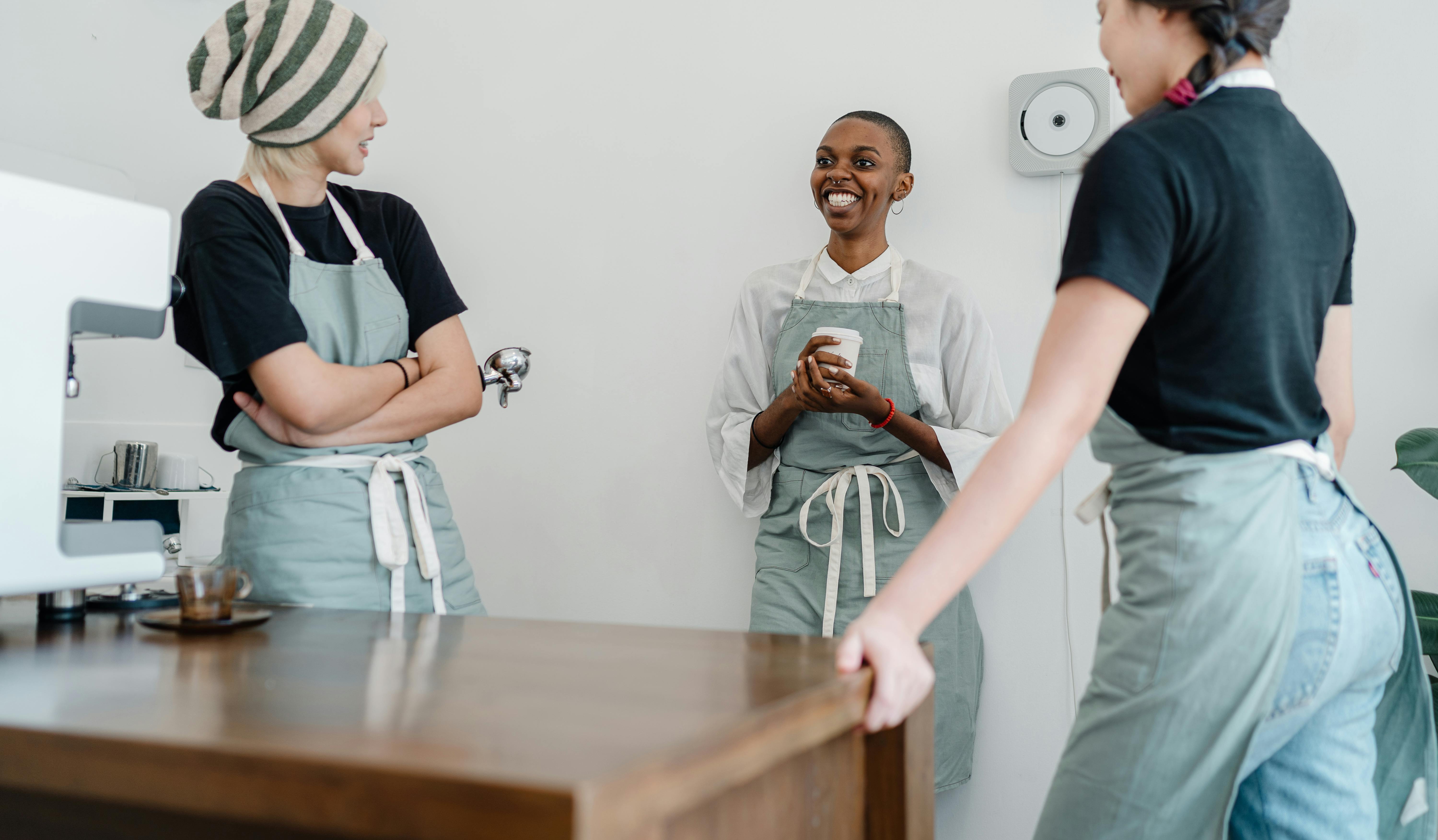 happy multiethnic female baristas discussing ideas during break