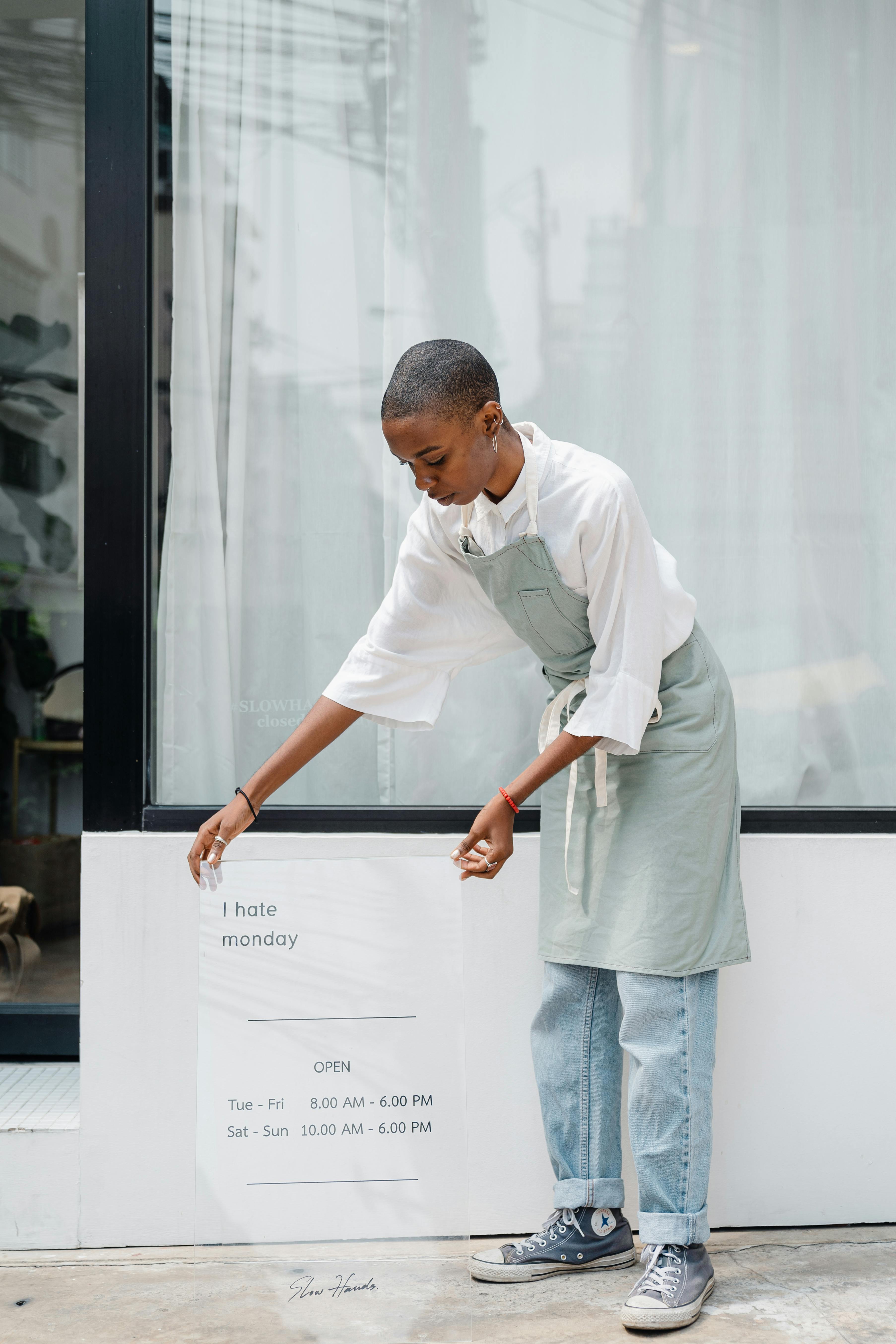 african american waitress with open sign against modern cafe