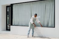 一位自信的年轻咖啡师在晨光中，于一家现代咖啡馆外竖起了户外标志