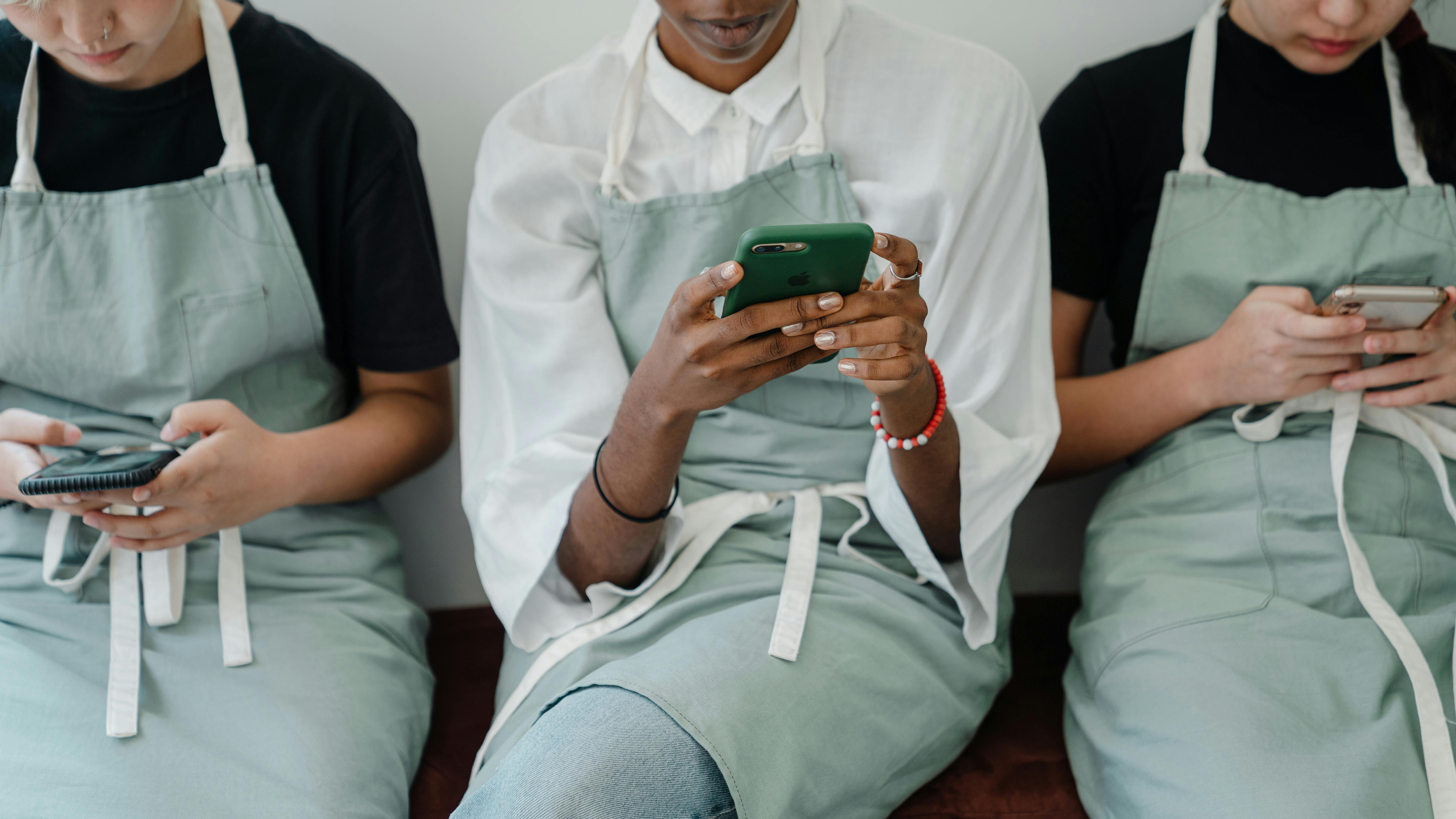 crop female multiracial coworkers browsing mobile phones during free time