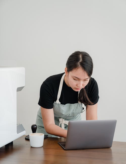 Concentrated barista using laptop at workplace