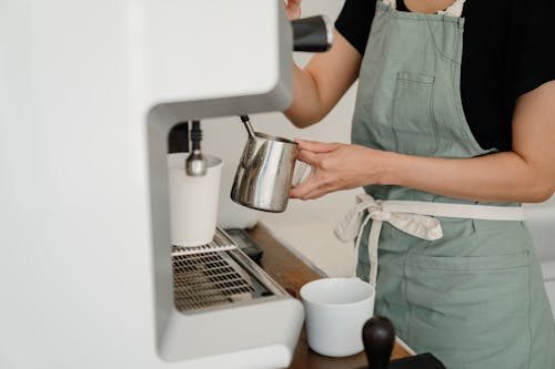 Crop barista preparing coffee in cafe