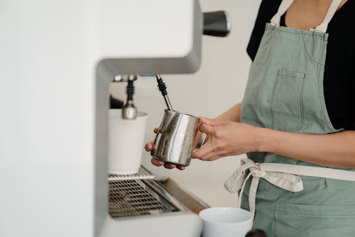Crop coffee house worker making coffee using coffee machine