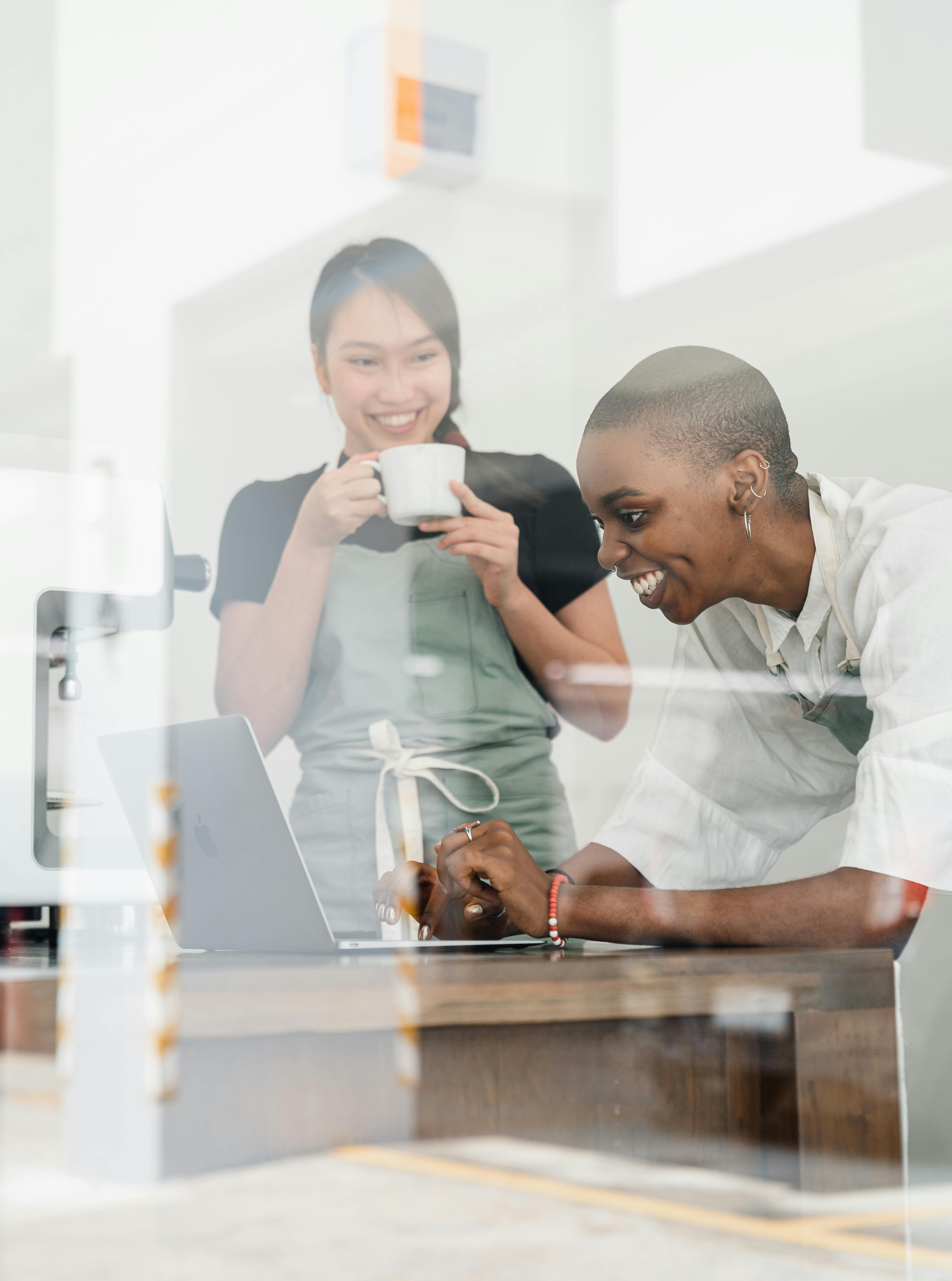 female baristas surfing net on laptop while having coffee break