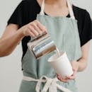 Unrecognizable female worker pouring milk into coffee cup