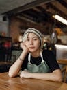 Female barista in beanie and apron resting chin on had