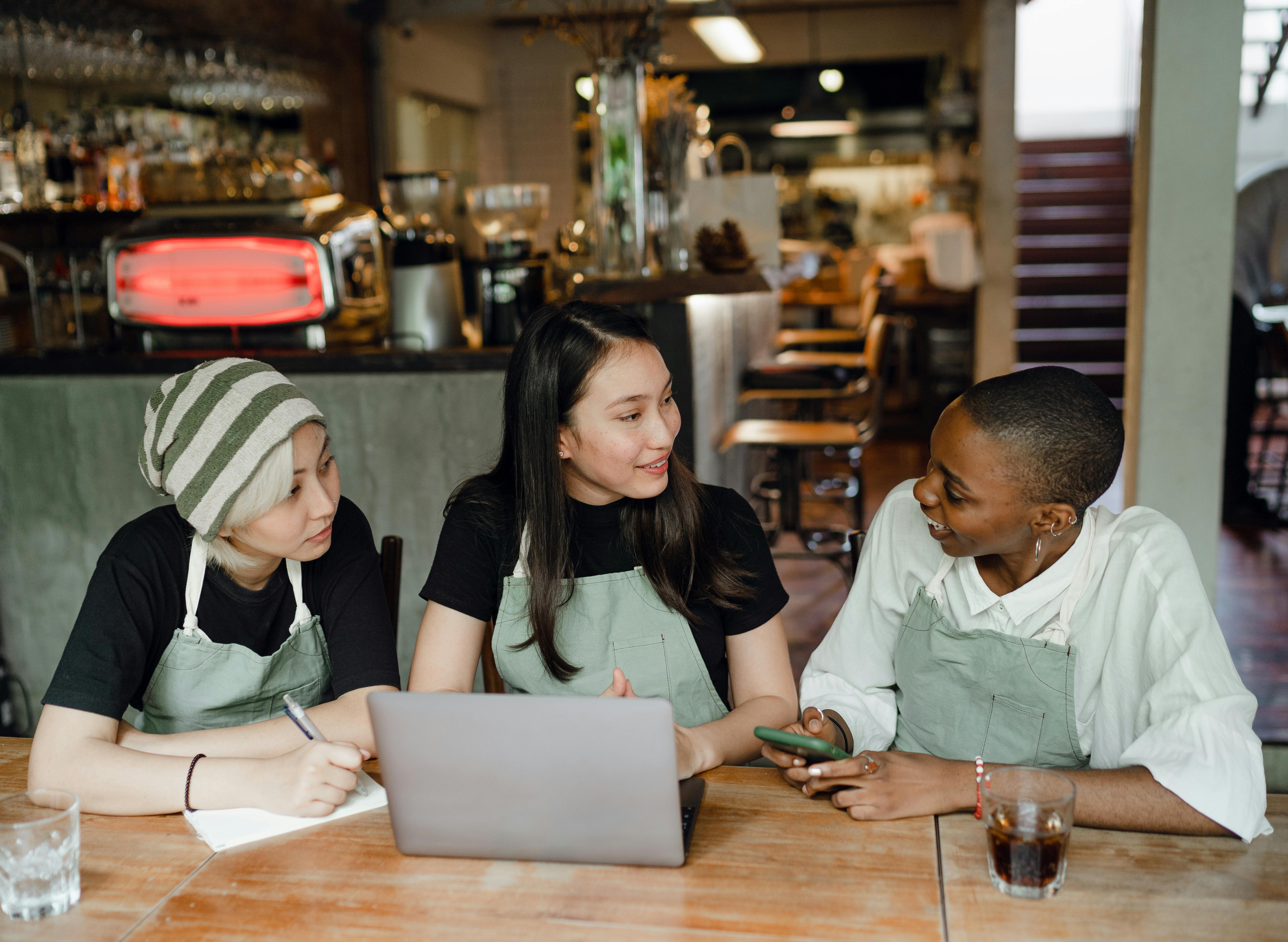 cheerful colleagues working on laptop in cafeteria