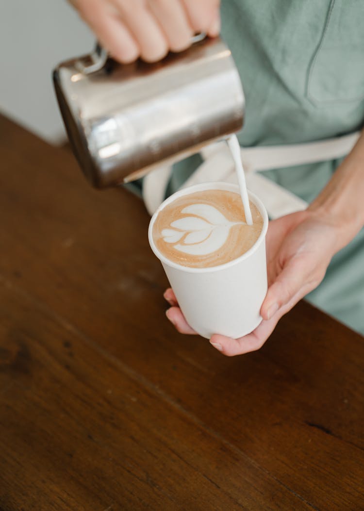 Crop Barista Pouring Steamed Milk Into Cup With Coffee