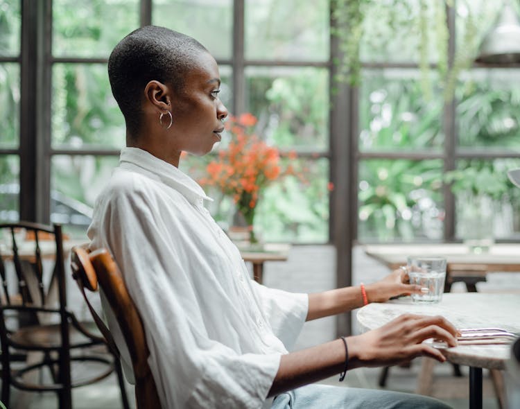 Thoughtful Woman In Stylish Wear Sitting At Table In Restaurant