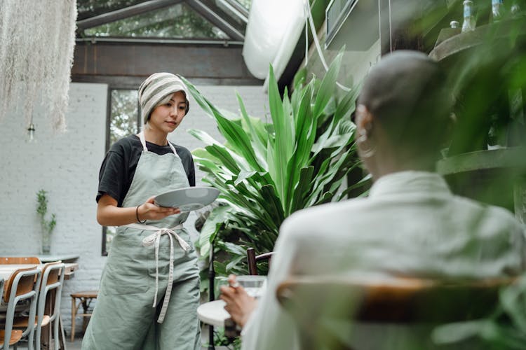 Calm Waitress With Plate Serving Restaurant Guest