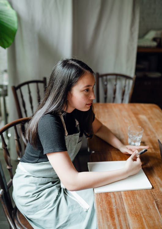 Young waitress with notebook sitting at table