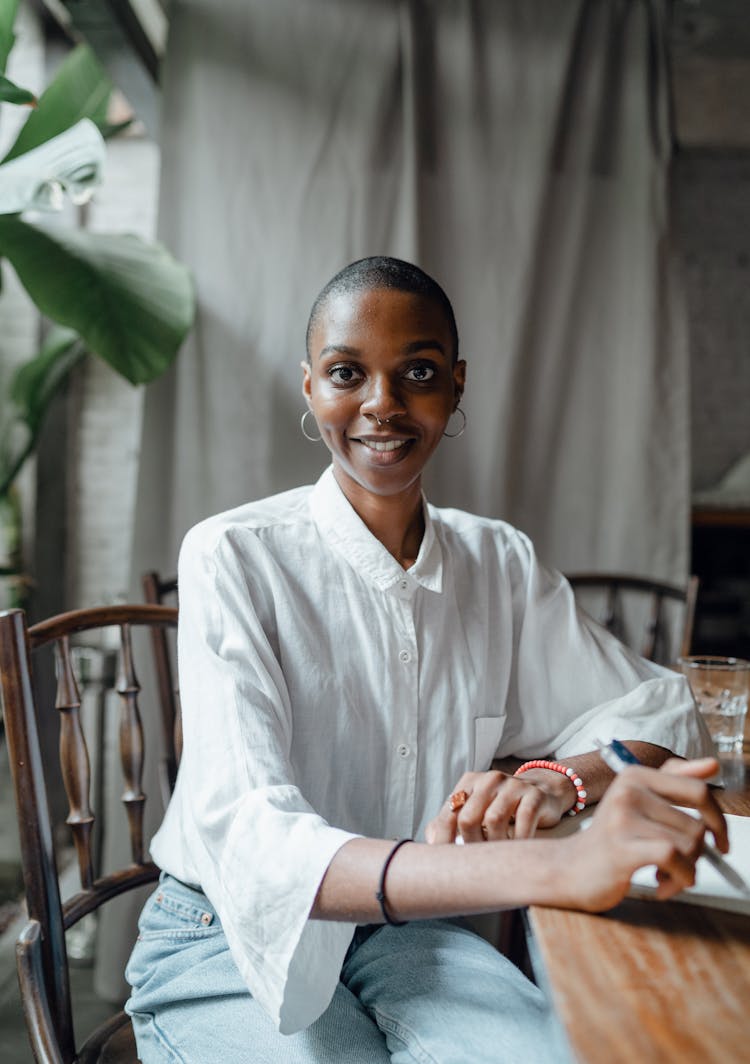 Cheerful Woman With Notebook Sitting At Table