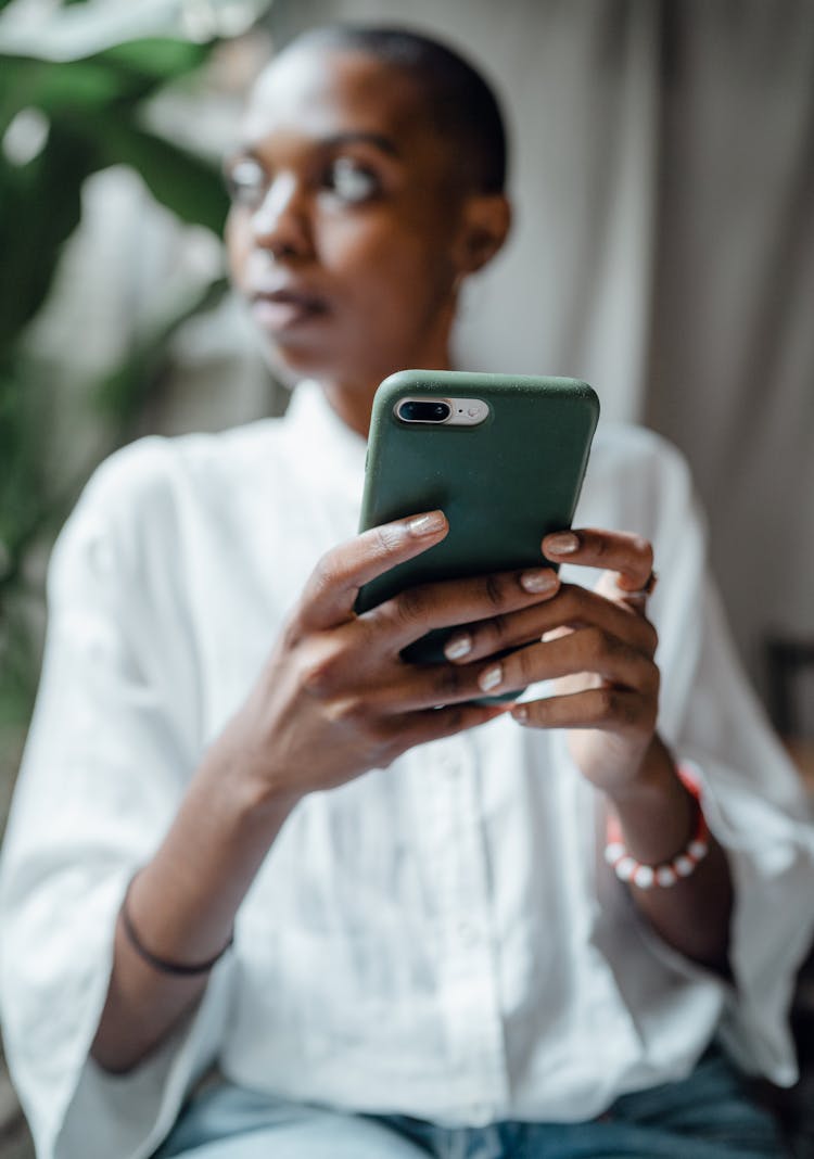 Black Woman Using Smartphone And Looking Away