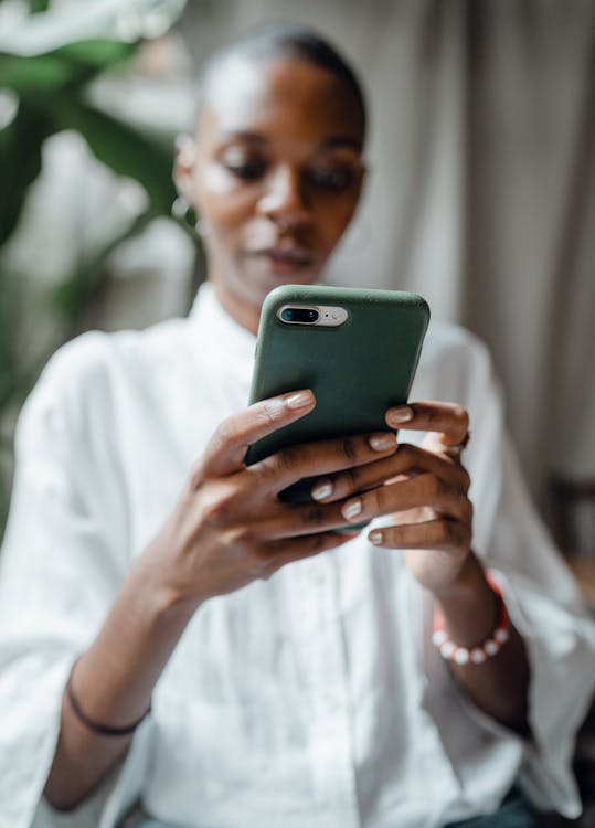 Free Black woman messaging on modern cellphone Stock Photo