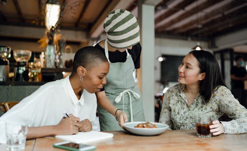 Free Cheerful women tasting new menu food in cafe Stock Photo