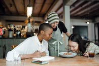 Cheerful coworkers tasting and smelling food in restaurant