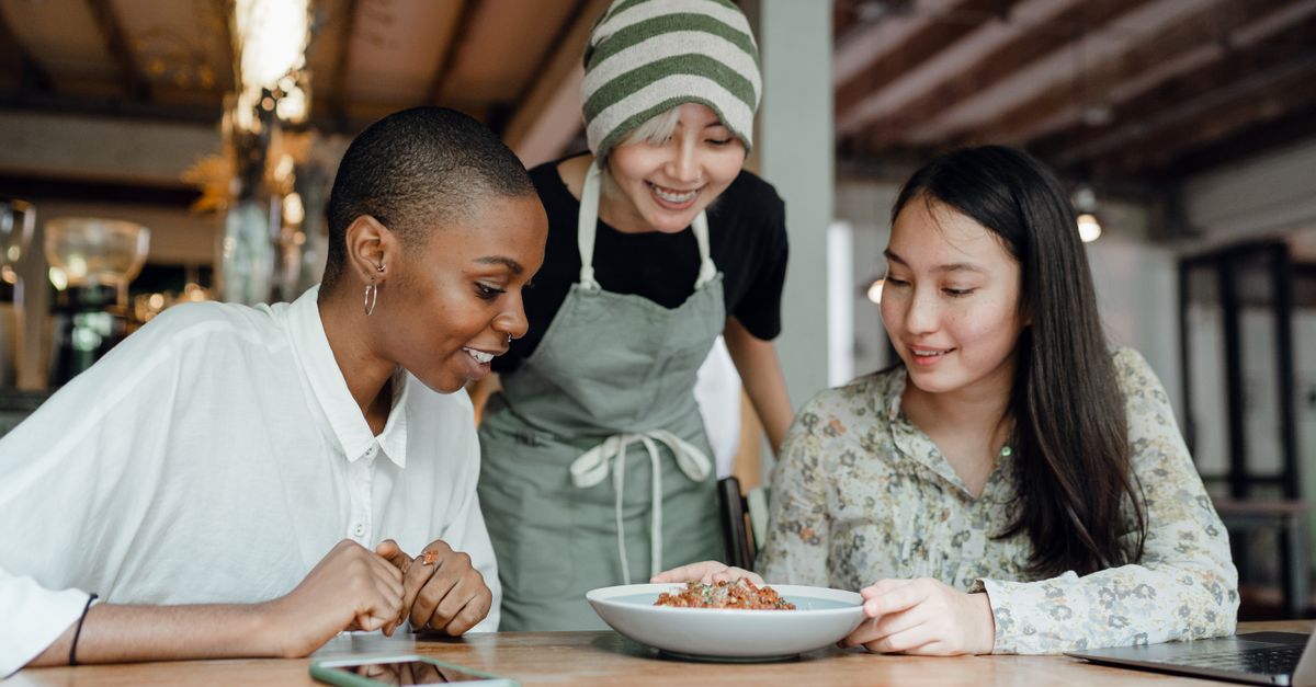 diverse group of people laughing and sharing a meal, mix of locals and foreigners in a casual setting