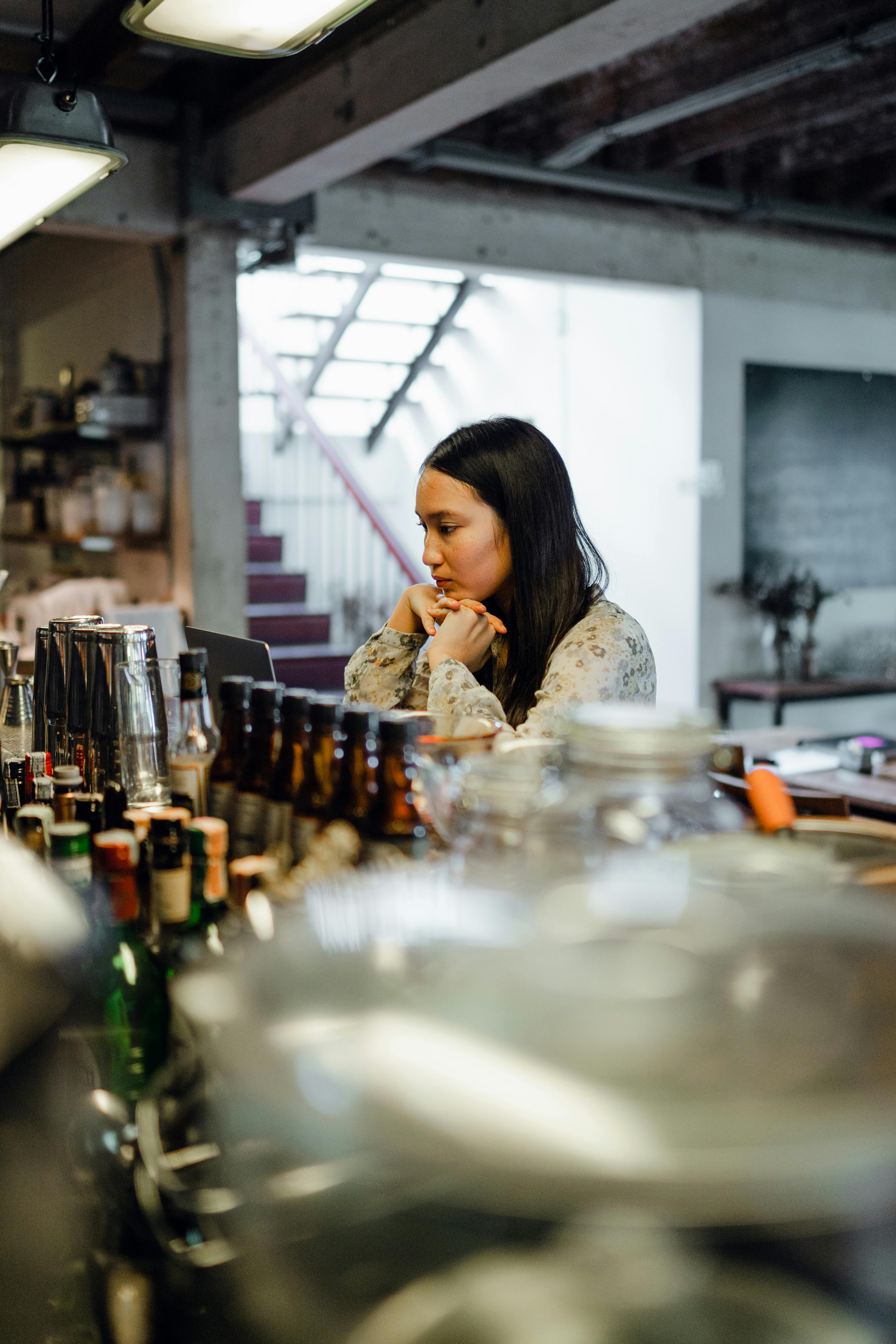 young melancholic ethnic woman using laptop in bar