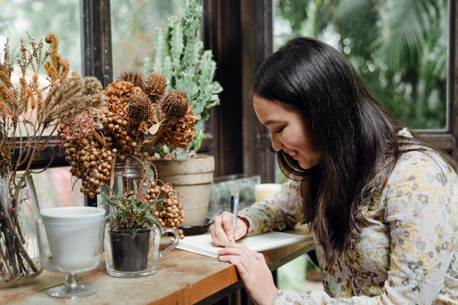 A wedding planner writing notes beside dried flowers