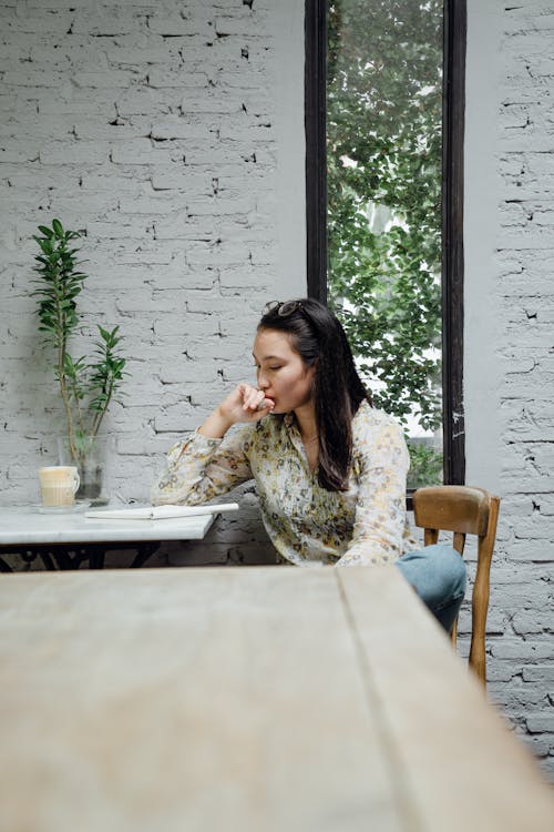 Focused young Asian woman thinking about project in cafeteria