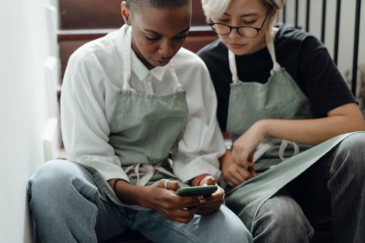 Stylish Diverse Female Friends Watching Video On Smartphone