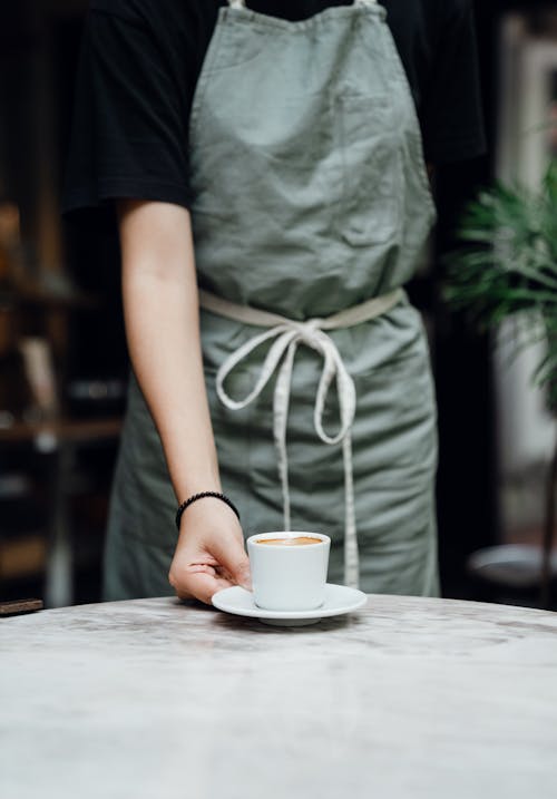 Crop waitress serving cup of coffee