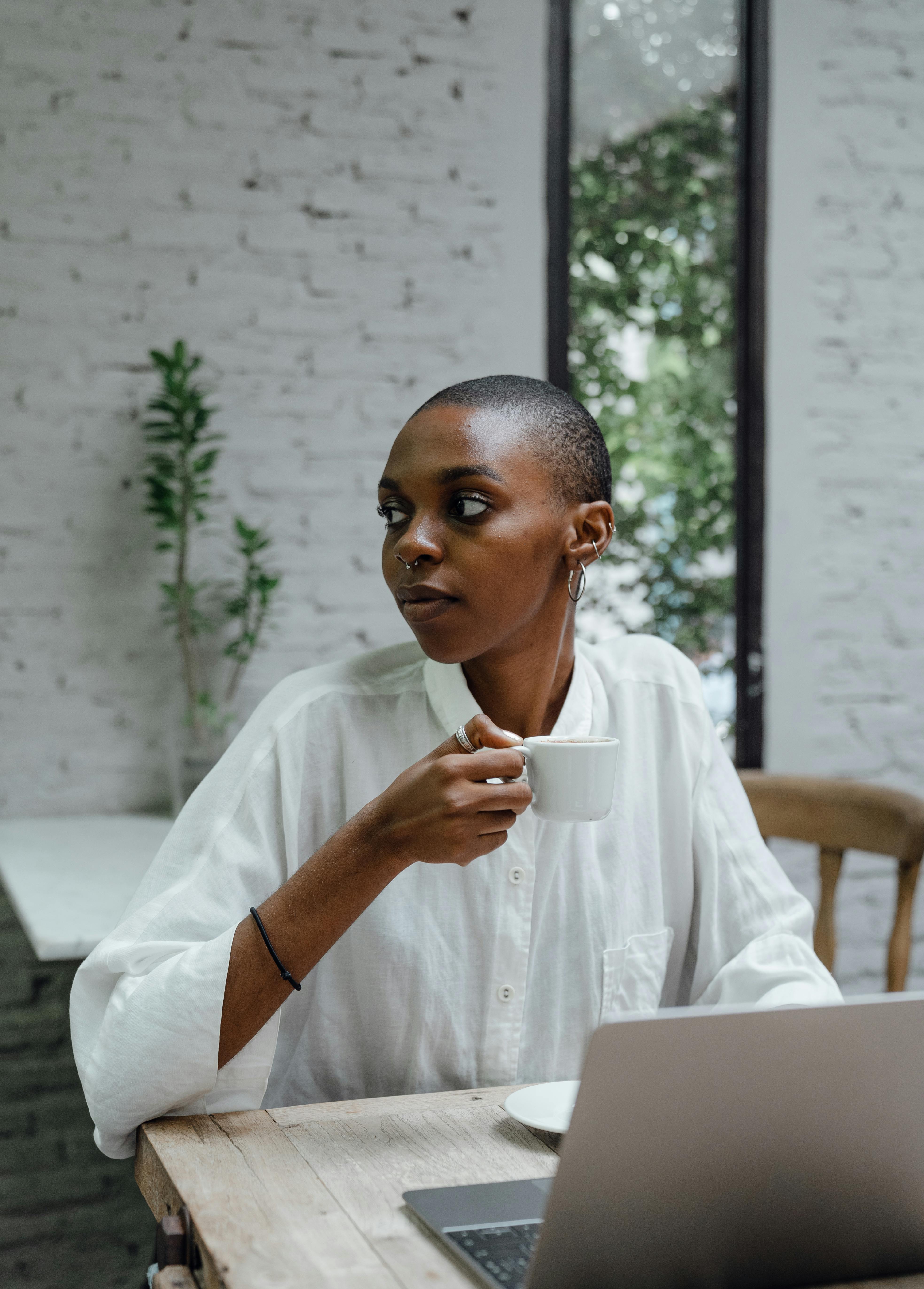 elegant black lady using laptop while enjoying coffee in cafe