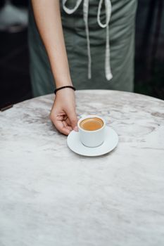 一名咖啡师在大理石桌上为顾客端上新鲜的浓缩咖啡，背景是现代咖啡馆