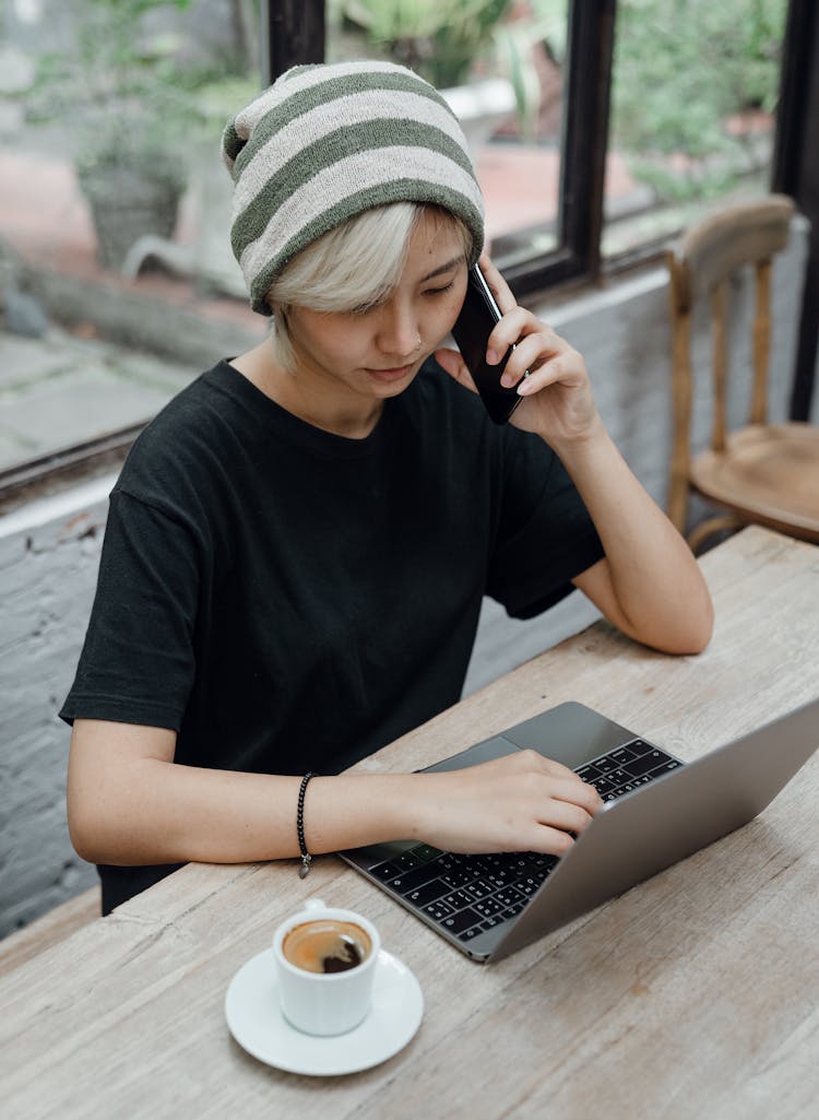 Young Woman Working On Laptop And Making Phone Call