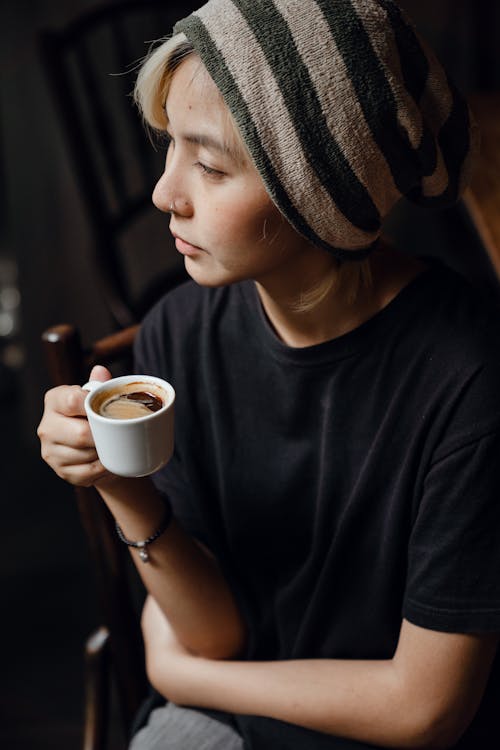 Young pensive lady in casual wear drinking coffee