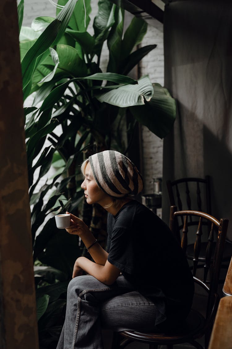 Pensive Woman Enjoying Coffee Alone While Looking Out Window