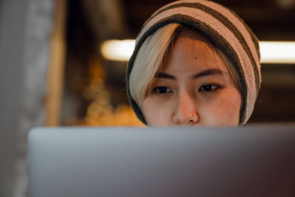 A focused person reads a computer screen in a café, like a prospect discovering your page