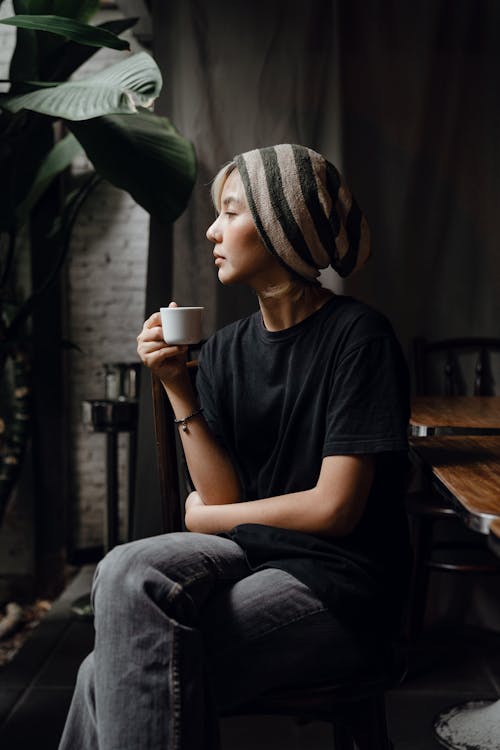 Slender Asian female having cup of coffee in quiet cafe