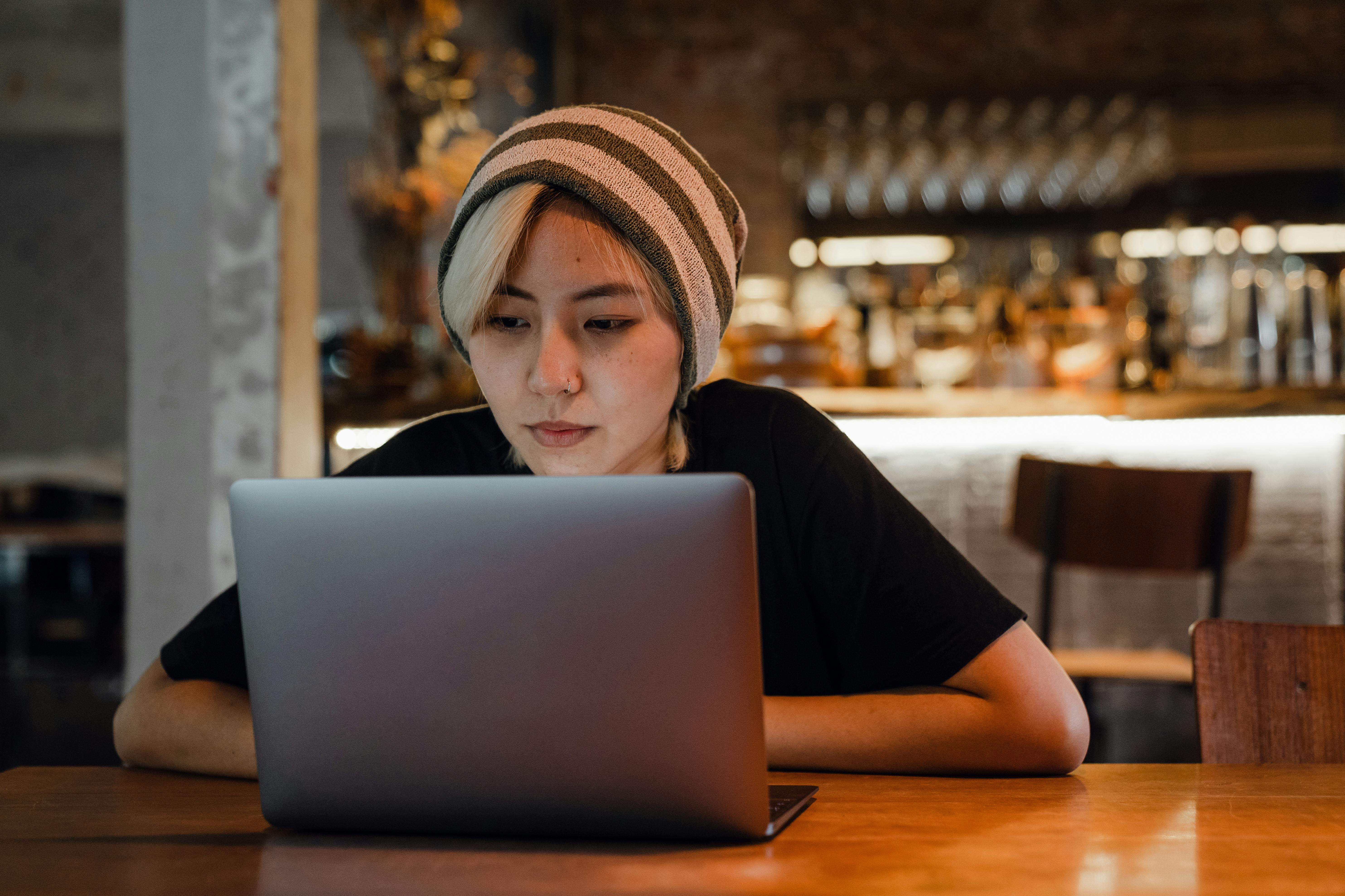 young woman watching movie on laptop in cafe