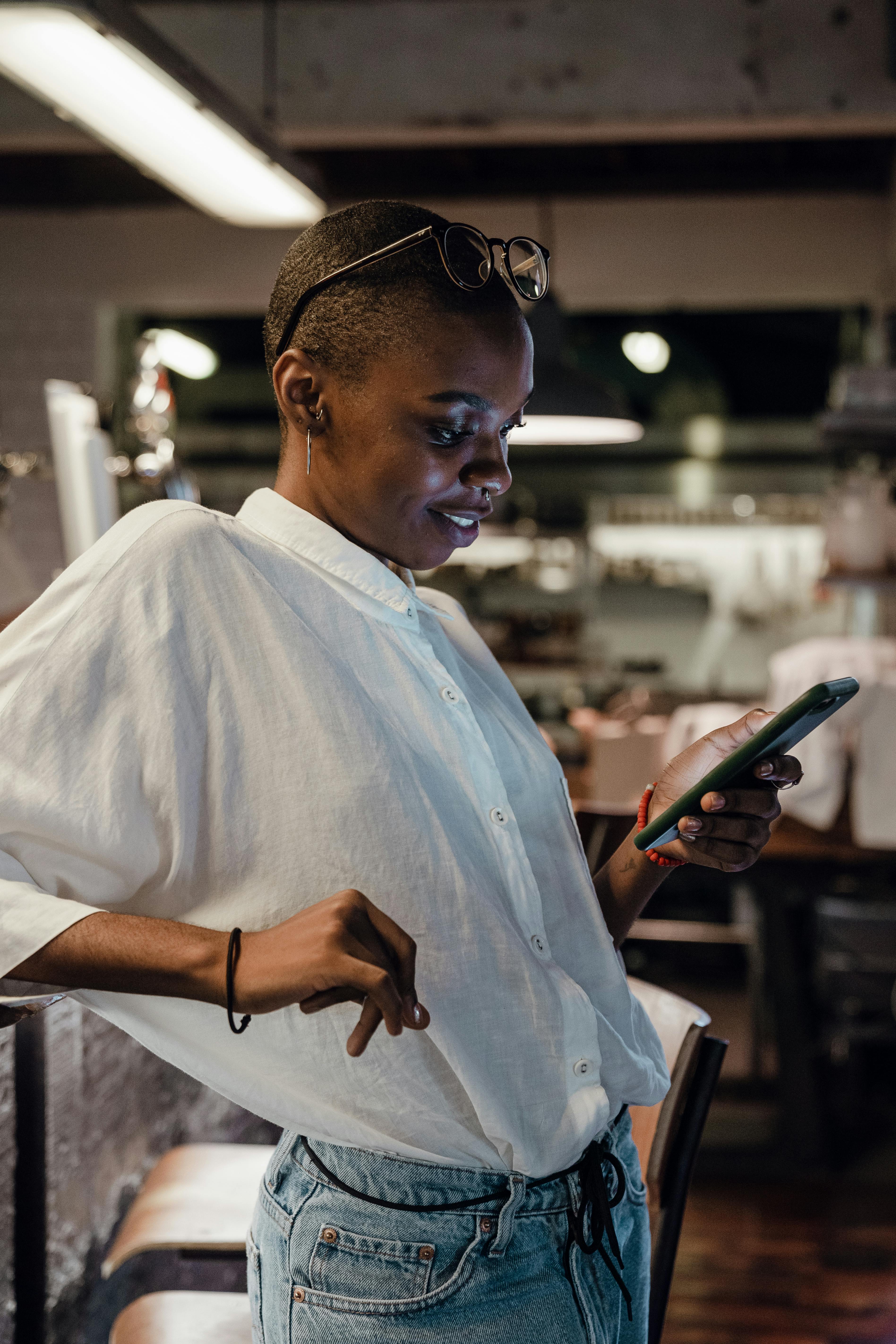 content black female using smartphone in bar