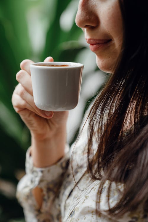 Crop woman tasting fresh coffee in cafe